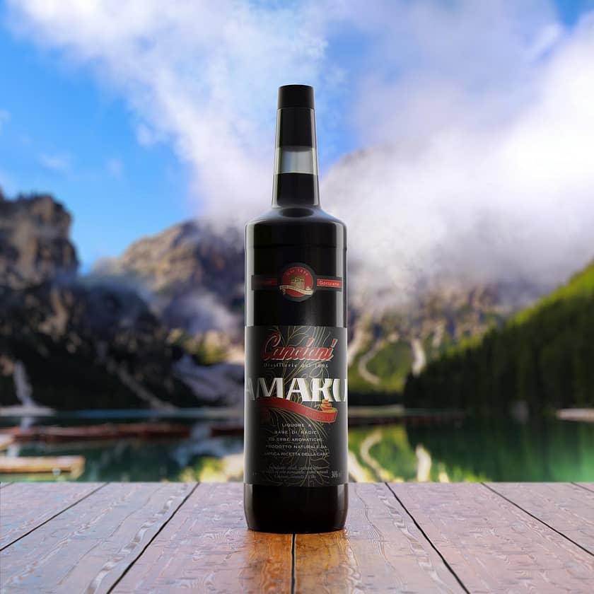 una bottiglia di amaro Canciani fotografata su un tavolo in legno, con una montagna e cielo sullo sfondo
